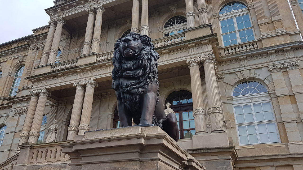 statue, architecture, sculpture, human representation, building exterior, male likeness, art and craft, built structure, low angle view, history, outdoors, day, travel destinations, no people, lion - feline, city, sky, mammal