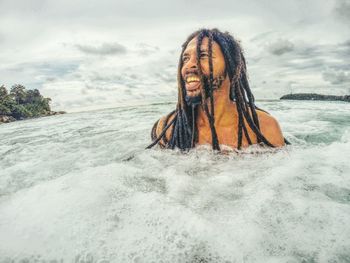 Man with dreadlocks swimming in sea