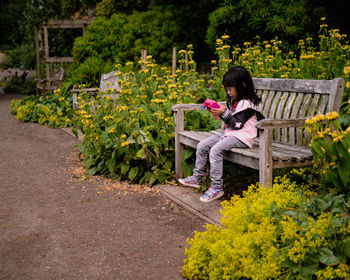 Girl sitting on chair checking her camera at summer garden  