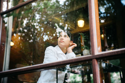 Low angle view of woman looking away while standing by railing