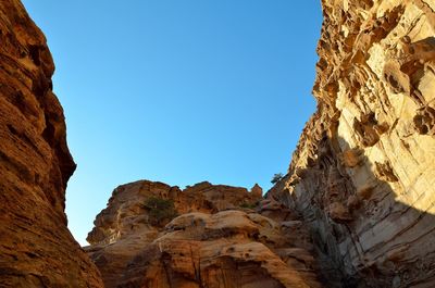 Low angle view of rocky mountain against blue sky