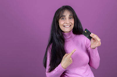 Caucasian brunette woman with long hair, smiling, showing credit card