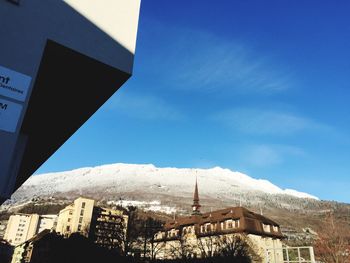 Low angle view of buildings and mountain against blue sky