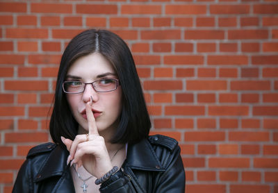 Portrait of a young woman against brick wall