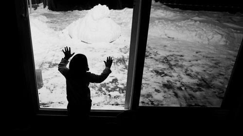 Silhouette boy standing by window