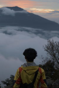 Rear view of man looking at mountain against sky