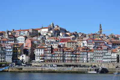 Townscape by river against clear blue sky