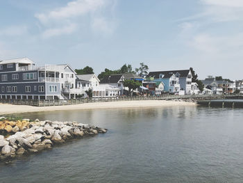 Buildings by sea against sky