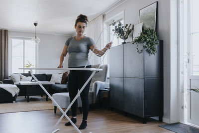 Pregnant woman doing housework and setting up clothes drying rack