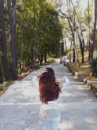 Rear view of woman walking on footpath amidst trees