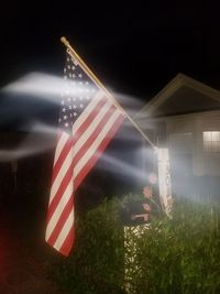 Illuminated flags against sky at night