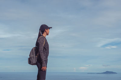 Side view of woman standing in sea against sky