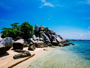 Rocks on beach against blue sky