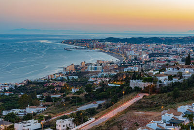 High angle view of townscape by sea against sky during sunset