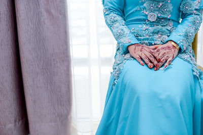 Midsection of bride sitting at home