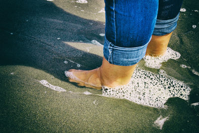 Low section of person standing at sea shore