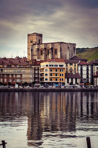 Buildings by lake against sky in city