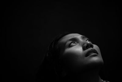 Close-up of thoughtful woman against black background