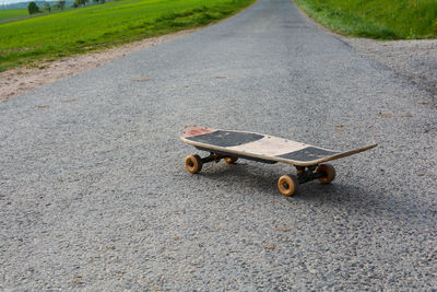 Old skateboard stands on a lonely country road in green nature