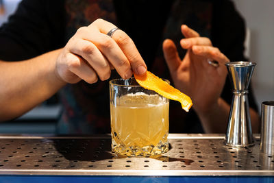 Midsection of woman holding drink on table