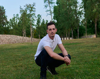 Portrait of young man exercising on field