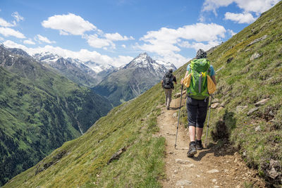 Rear view of man walking on mountain against sky