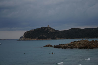 Scenic view of sea and mountain against cloudy sky