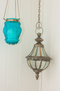 Close-up of electric lamp hanging against blue wall