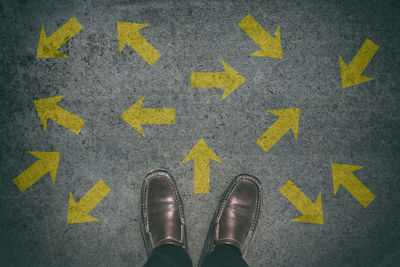 Low section of person standing on road sign