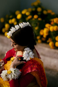 Close-up of woman with red rose against blurred background