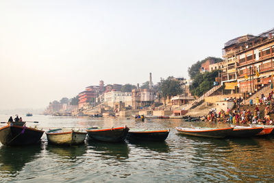 Boats in canal amidst buildings in city against sky