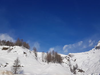 Scenic view of snow covered mountains against blue sky