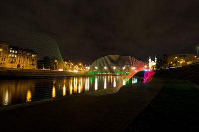 Illuminated city by river at night