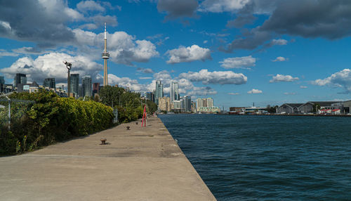 City at waterfront against cloudy sky