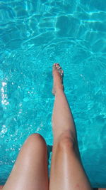 Low section of woman enjoying in swimming pool on sunny day