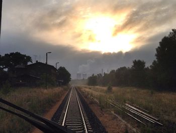 Railroad tracks against cloudy sky