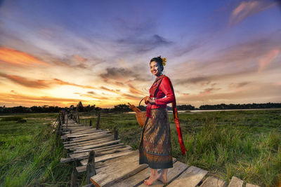 Boy standing on field against sky during sunset