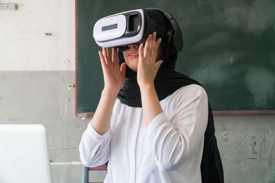 Woman wearing virtual reality simulator at home