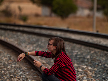 Girl sitting on railroad track