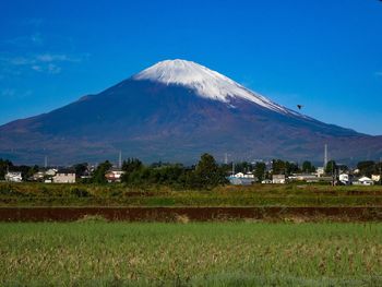 Scenic view of field and mountains against blue sky