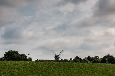 Traditional windmill on field against sky