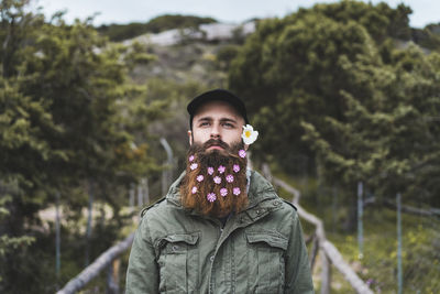 Portrait of young man standing against plants