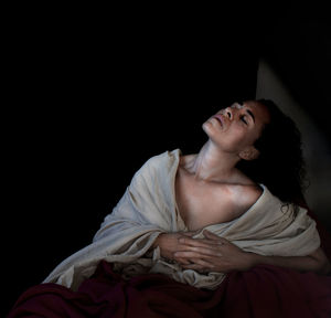 Midsection of woman looking away against black background