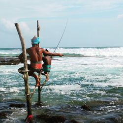 Full length of shirtless man in sea against sky