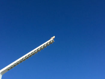 Low angle view of crane against clear blue sky