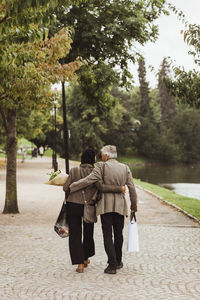 Rear view of senior couple walking on footpath in park