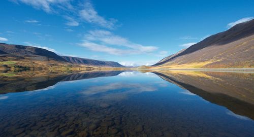 Scenic view of lake and mountains against blue sky