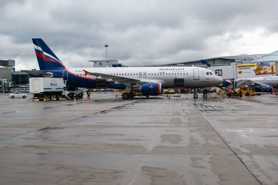 Airplane on airport runway against sky