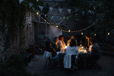 Multiracial friends during dinner party in illuminated back yard