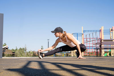 Woman in sportclothes working out on the sports ground in sunny summer day, warming up